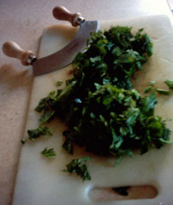 Chopped nettles on a board with a mezzaluna herb knife